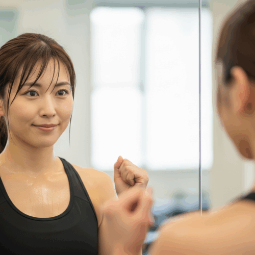 トレーニング後、鏡の中の自分に微笑む日本人女性